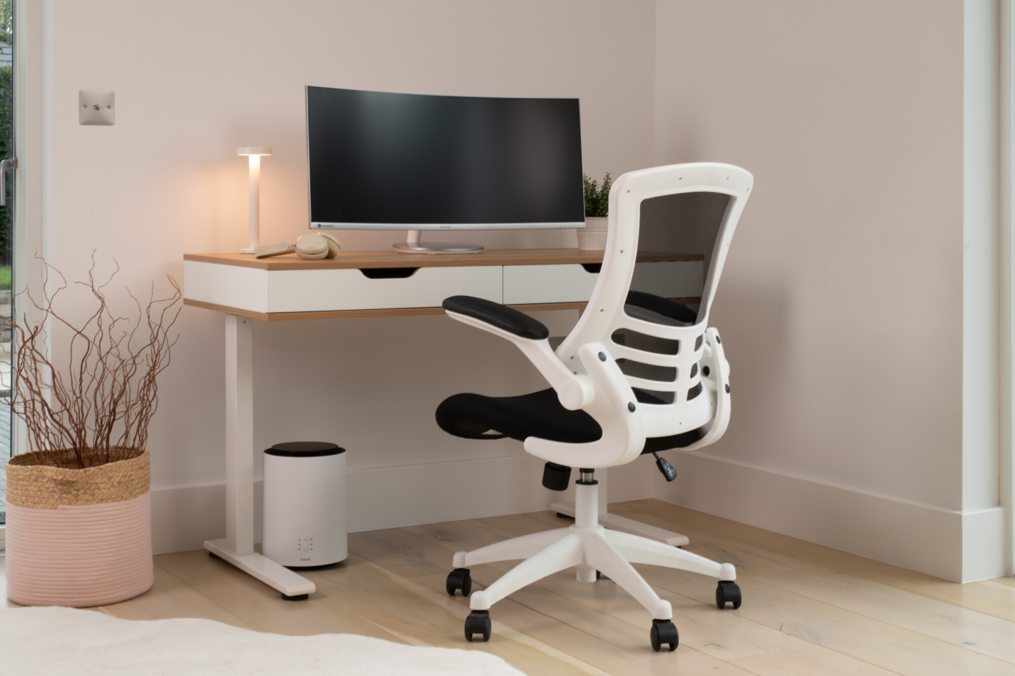 Kobles Ola oak and white height adjustable desk fills the background with the ergonomic Lukas mesh black and white body chair featuring front and centre. 