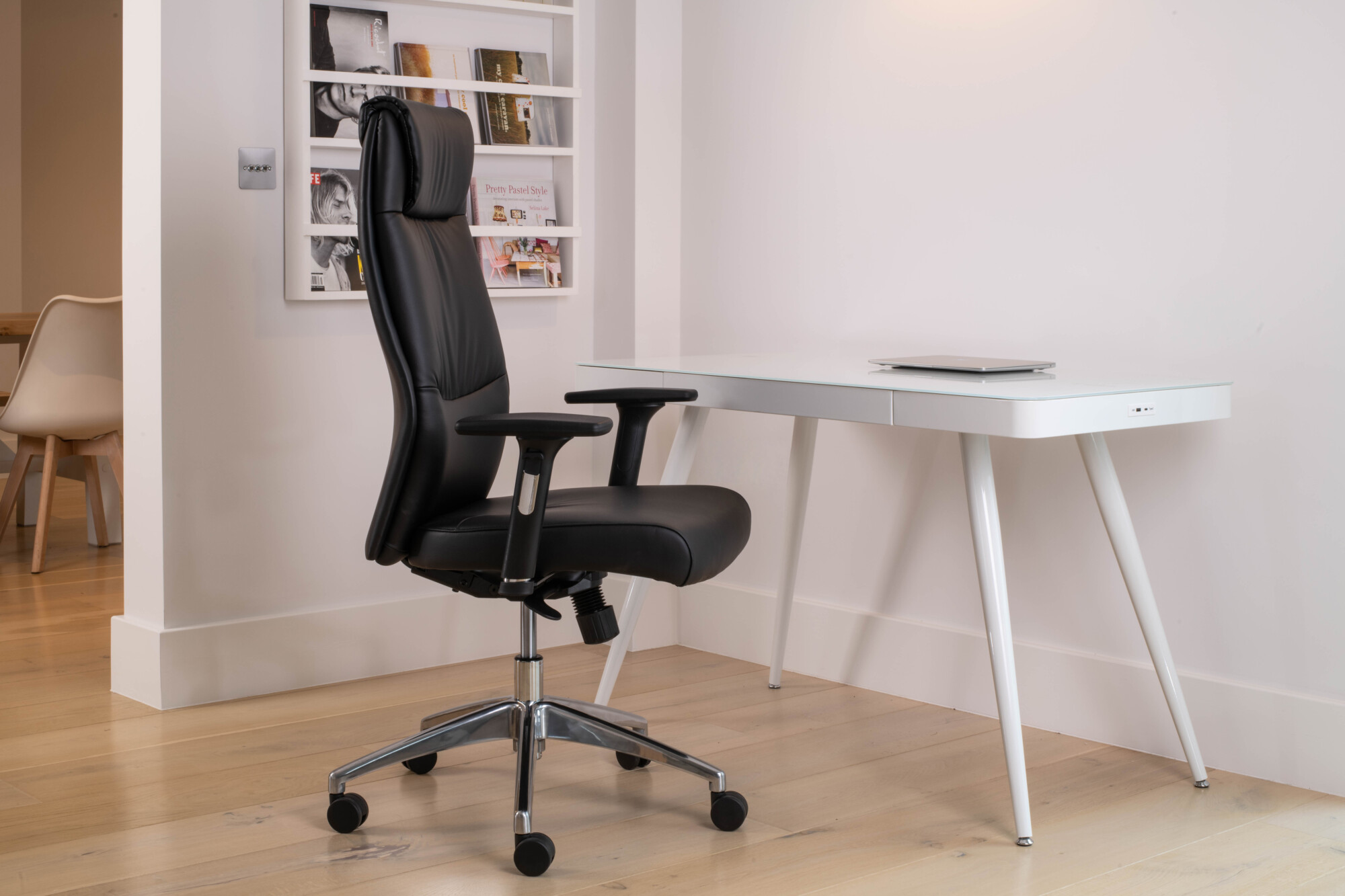 An all white smart desk paired with an all black faux leather chair. 