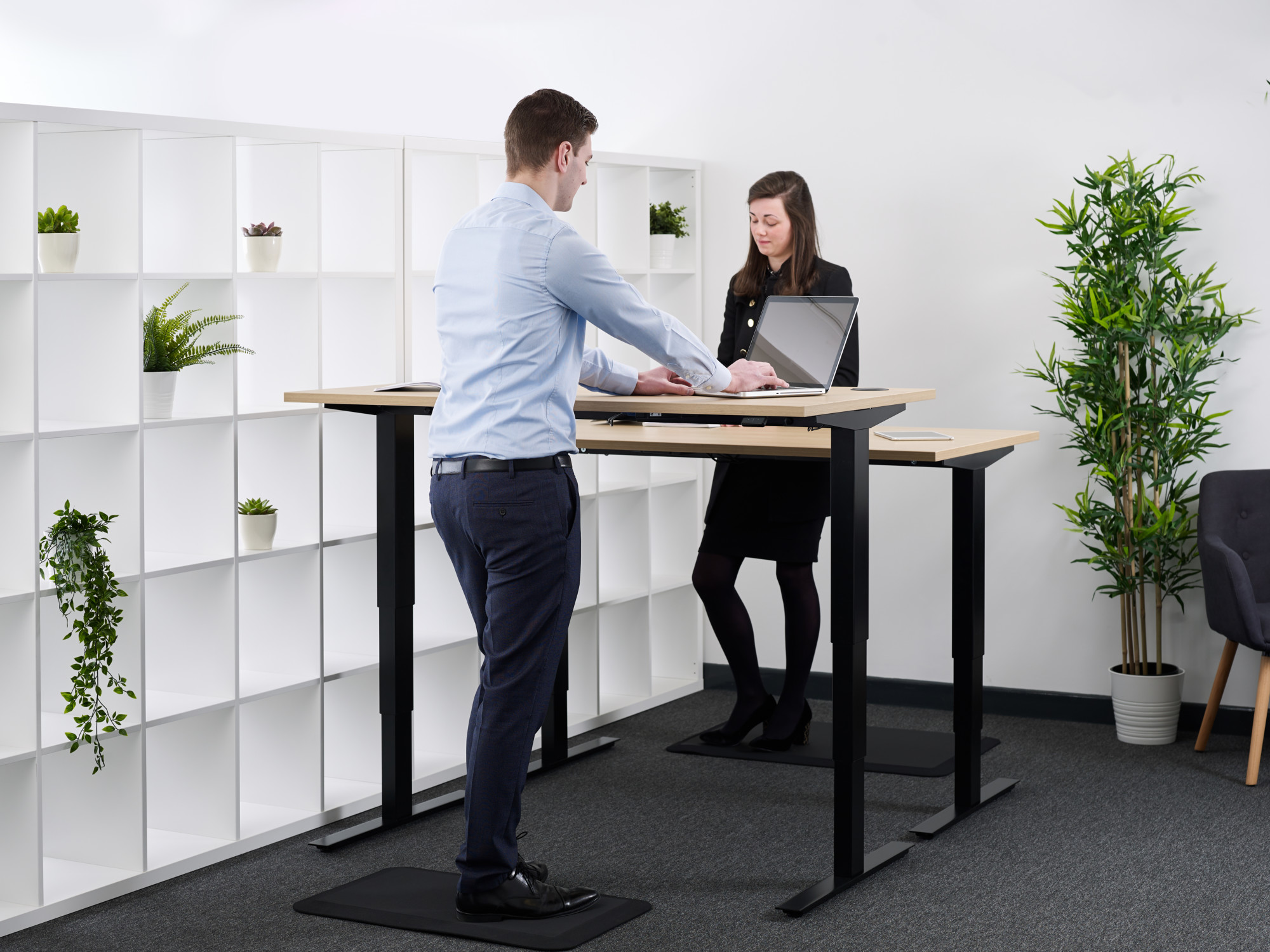 two people using standing desk at different heights