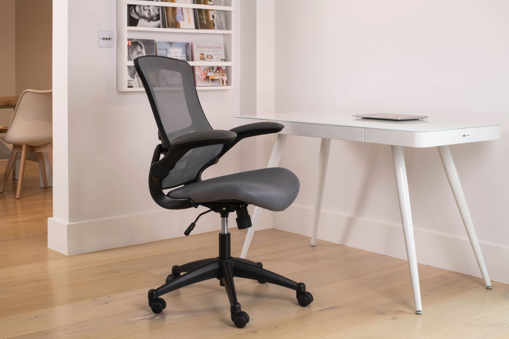 A white smart desk paired with a grey meshed and black body ergonomic chair. 