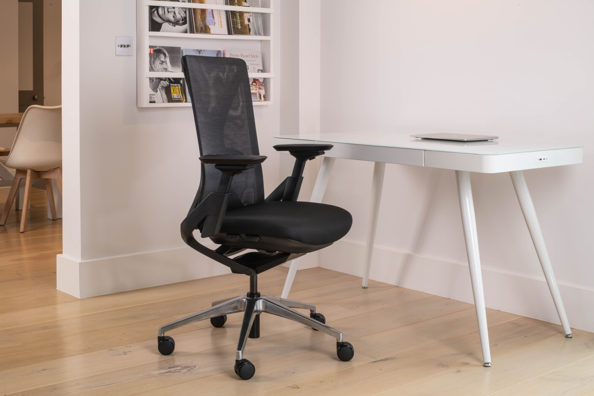 A white smart desk paired with a black meshed black ribcage body ergonomic chair. 