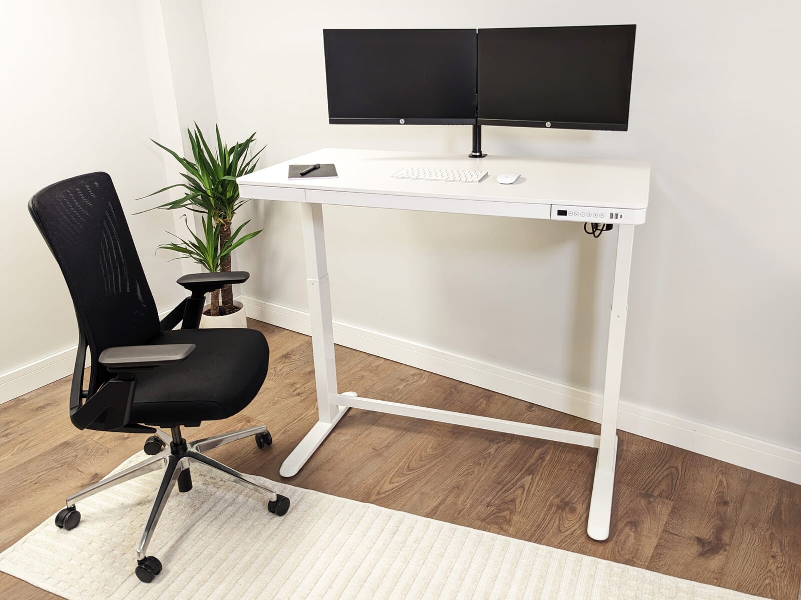 A white MFC Standing desk with a computer and a chair 